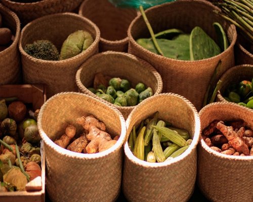 Fresh organic vegetables including avocados and nopales stacked neatly at a traditional Mexican city market